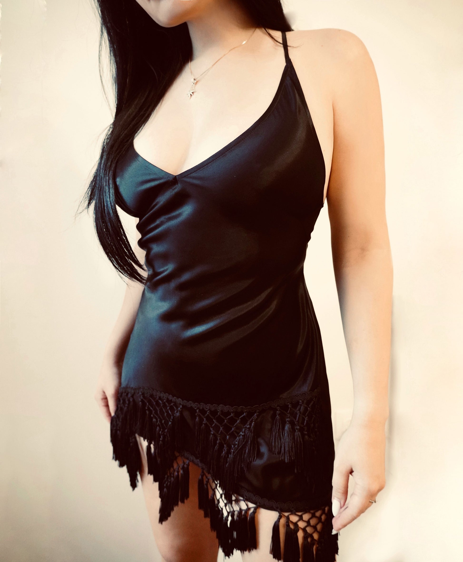 Beautiful girl in a black short viscose dress with fringes